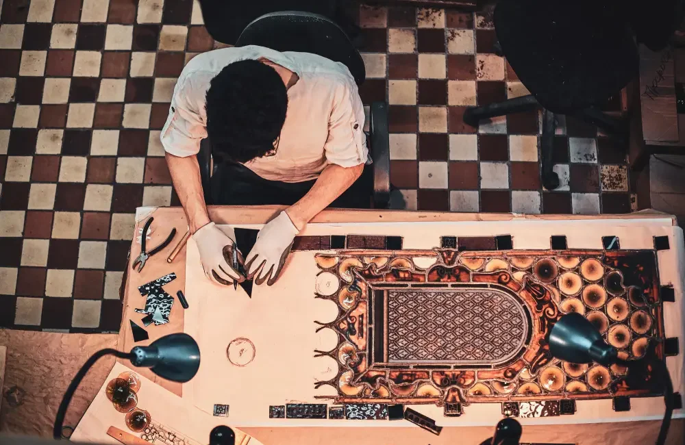 Mies työskentelee pöydän ääressä, jossa on koristeellinen pöytäliina.